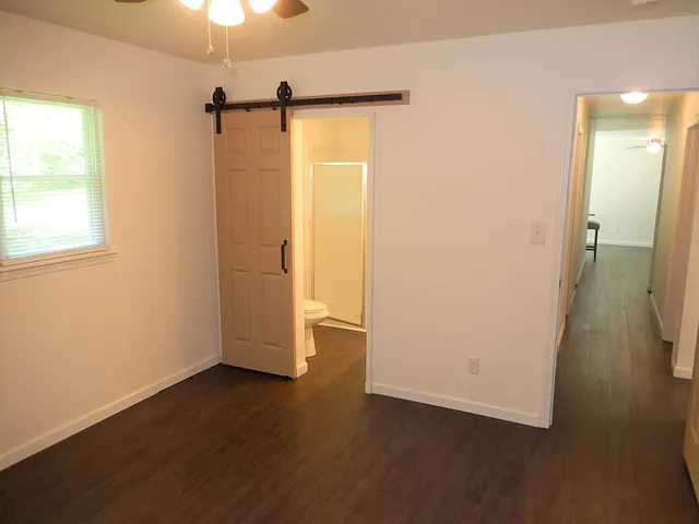 an empty room with wooden floor cabinet and windows