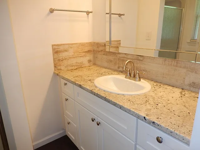 a bathroom with a granite countertop sink and a mirror