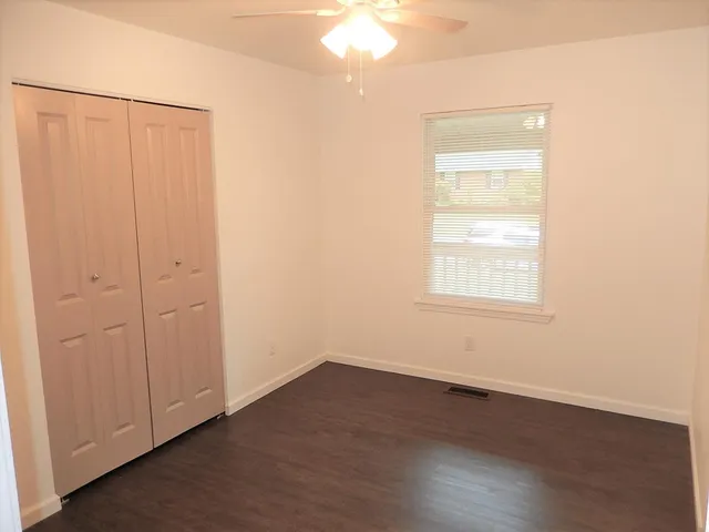an empty room with wooden floor and windows with curtains