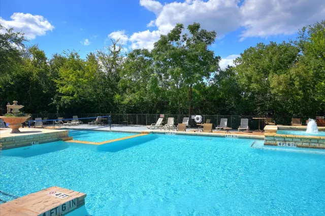 a view of a swimming pool with lawn chairs and plants