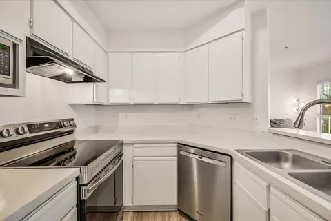 a kitchen with stainless steel appliances white cabinets and a stove top oven
