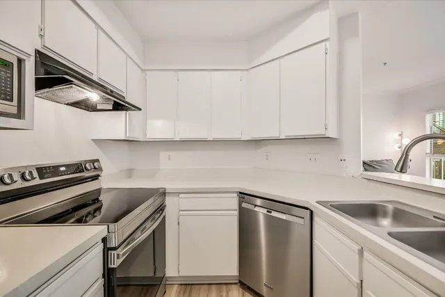 a kitchen with stainless steel appliances white cabinets and a stove top oven