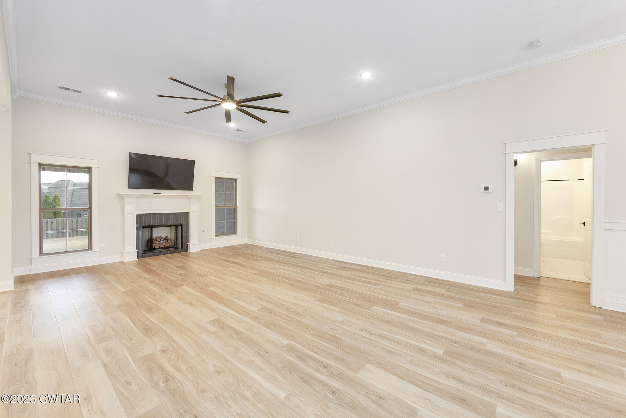 126 Isaiah Drive Jackson, TN 38305 - Photo 4 of 32 an empty room with wooden floor a flat screen tv and a fireplace