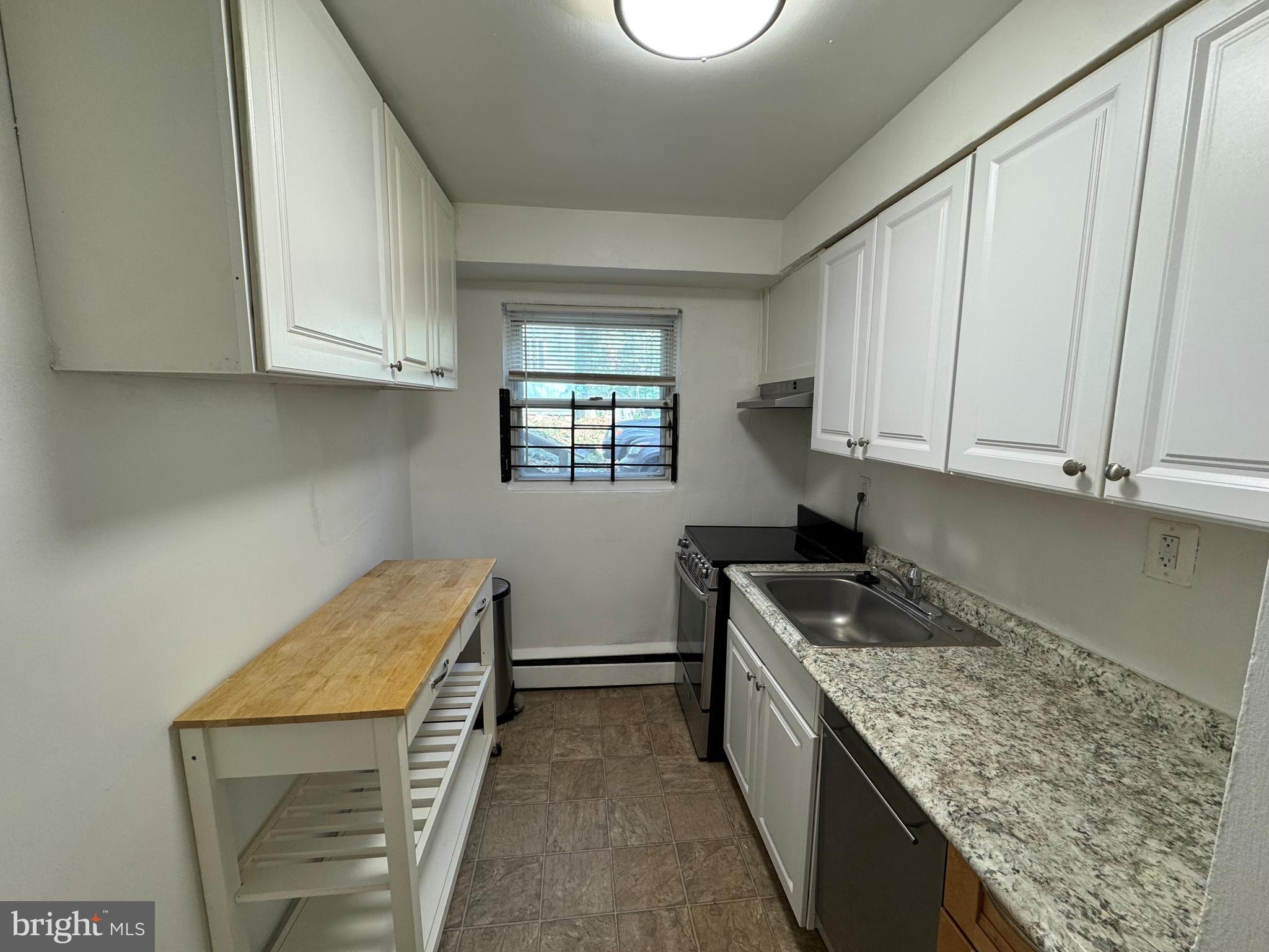 912 Prospect Street, Unit P1 Takoma Park, MD 20912 - Photo 7 of 8 a kitchen with granite countertop a sink a stove and cabinets
