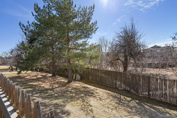 a view of a backyard with wooden fence and trees