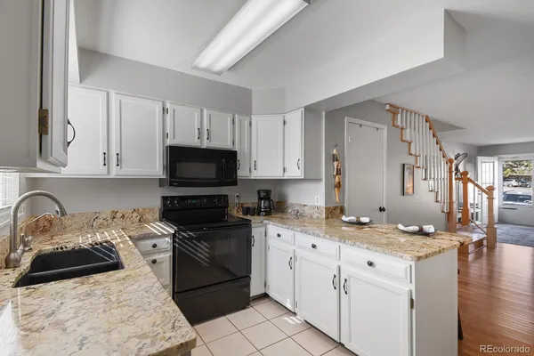 a kitchen with granite countertop a sink stove and cabinets
