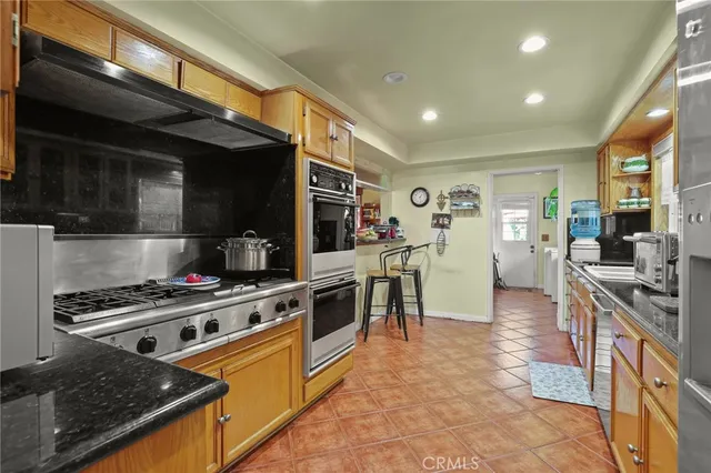 a large white kitchen with stainless steel appliances granite countertop a stove a sink and a microwave