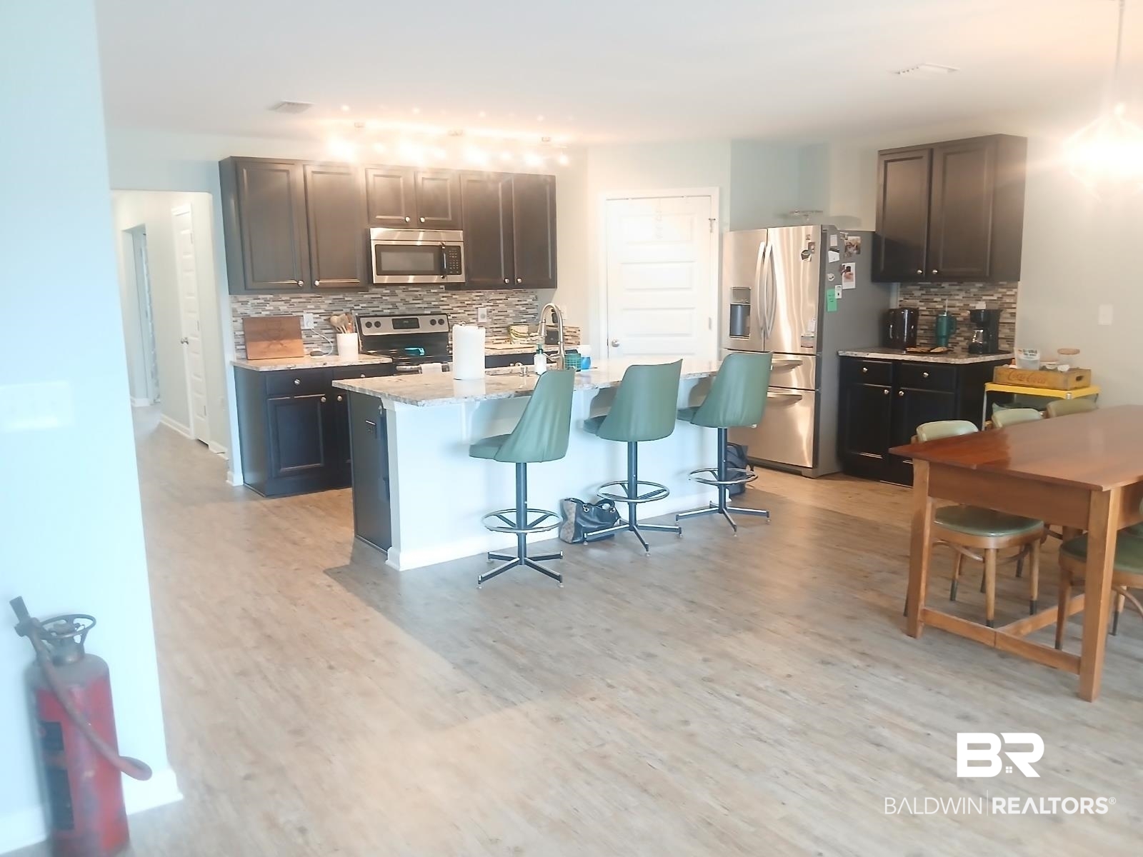 17431 Harding Drive Foley, AL 36535 - Photo 2 of 24 Kitchen featuring light hardwood / wood-style flooring, backsplash, light stone counters, appliances with stainless steel finishes, and a center island with sink