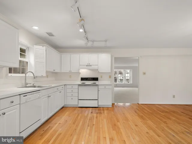 an empty room with wooden floor fireplace and windows