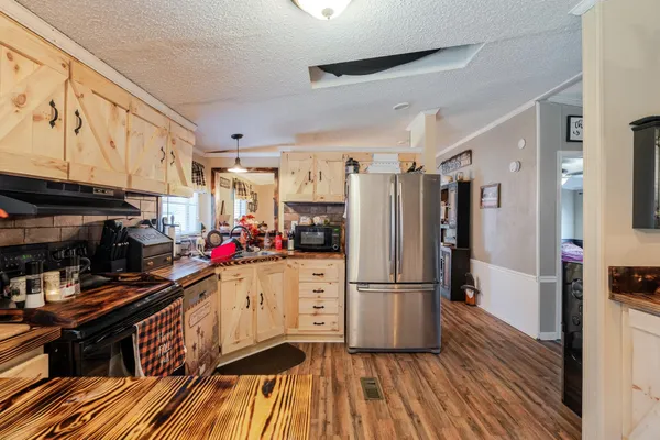 a kitchen with stainless steel appliances granite countertop a refrigerator cabinets and wooden floor