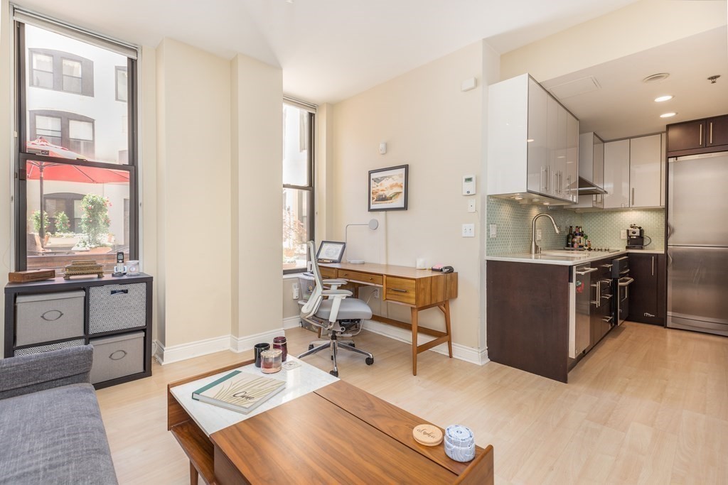 a living room with stainless steel appliances kitchen island granite countertop furniture a rug and a window