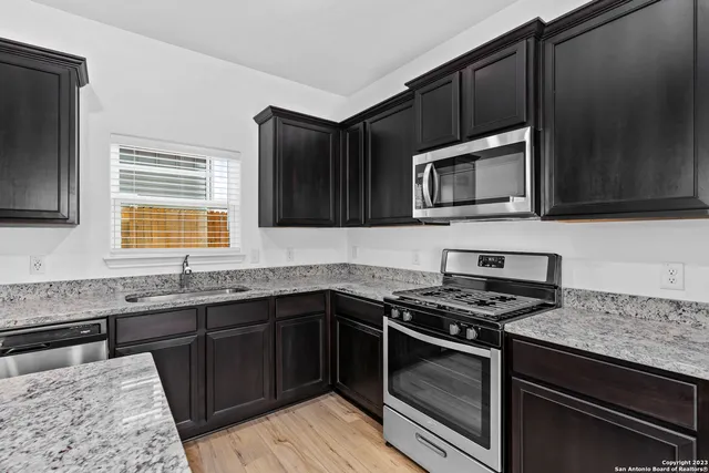 a kitchen with granite countertop stainless steel appliances a sink stove and microwave