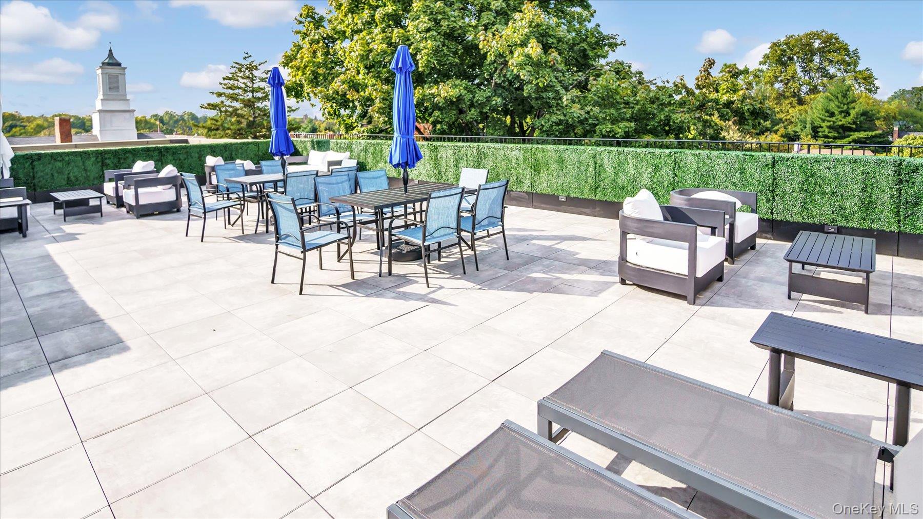 22 Park Place, Unit 4T Great Neck, NY 11021 - Photo 11 of 13 a view of a patio with couches and table and chairs under an umbrella