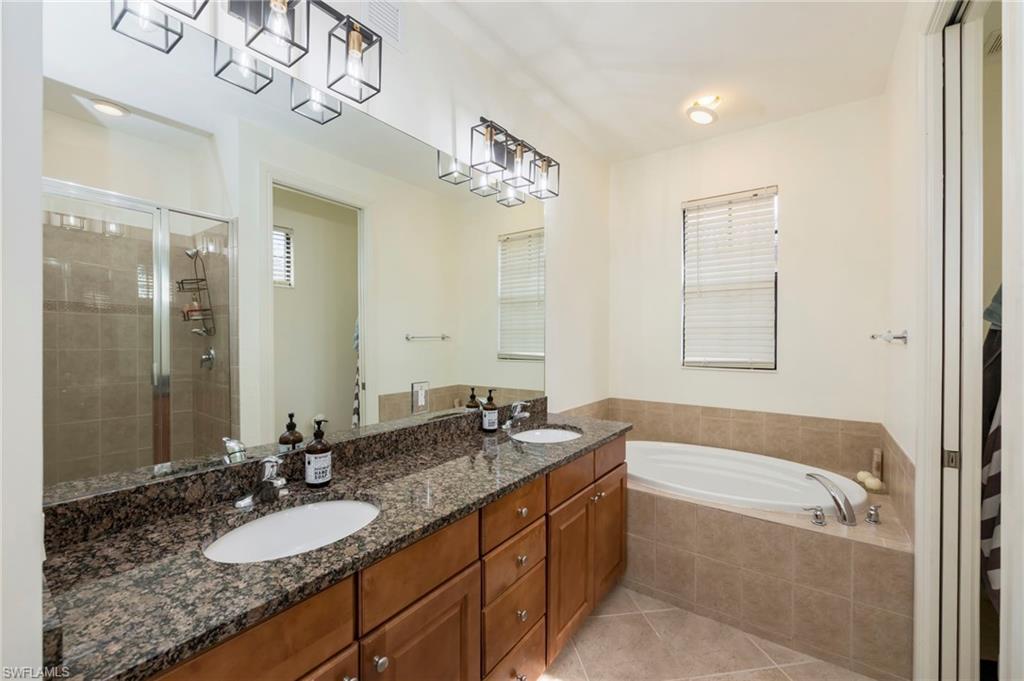 9145 Chula Vista Street, Unit 13004 Naples, FL 34113 - Photo 12 of 24 a bathroom with a granite countertop bathtub sink and mirror