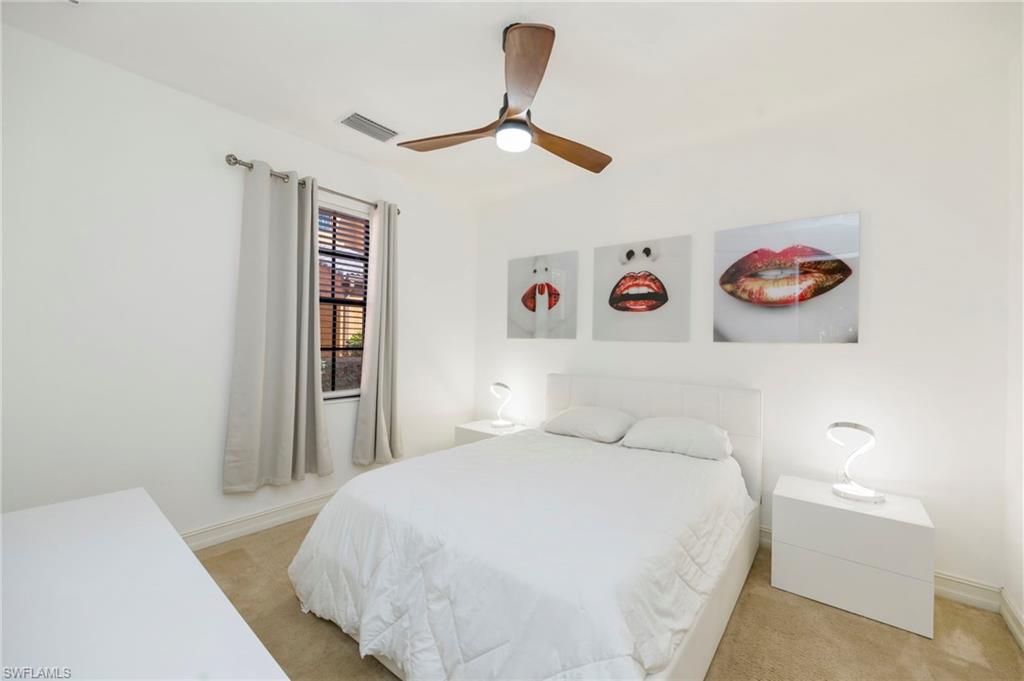 9145 Chula Vista Street, Unit 13004 Naples, FL 34113 - Photo 17 of 24 a bedroom with a large bed and a chandelier
