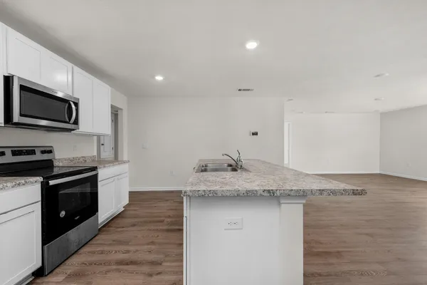 a kitchen with granite countertop stainless steel appliances a stove microwave and cabinets