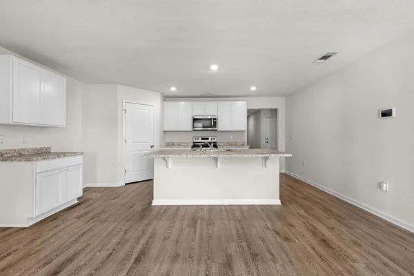 a view of a kitchen with wooden floor and stainless steel appliances