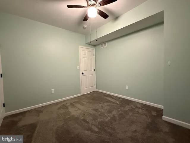 an empty room with a ceiling fan and a window