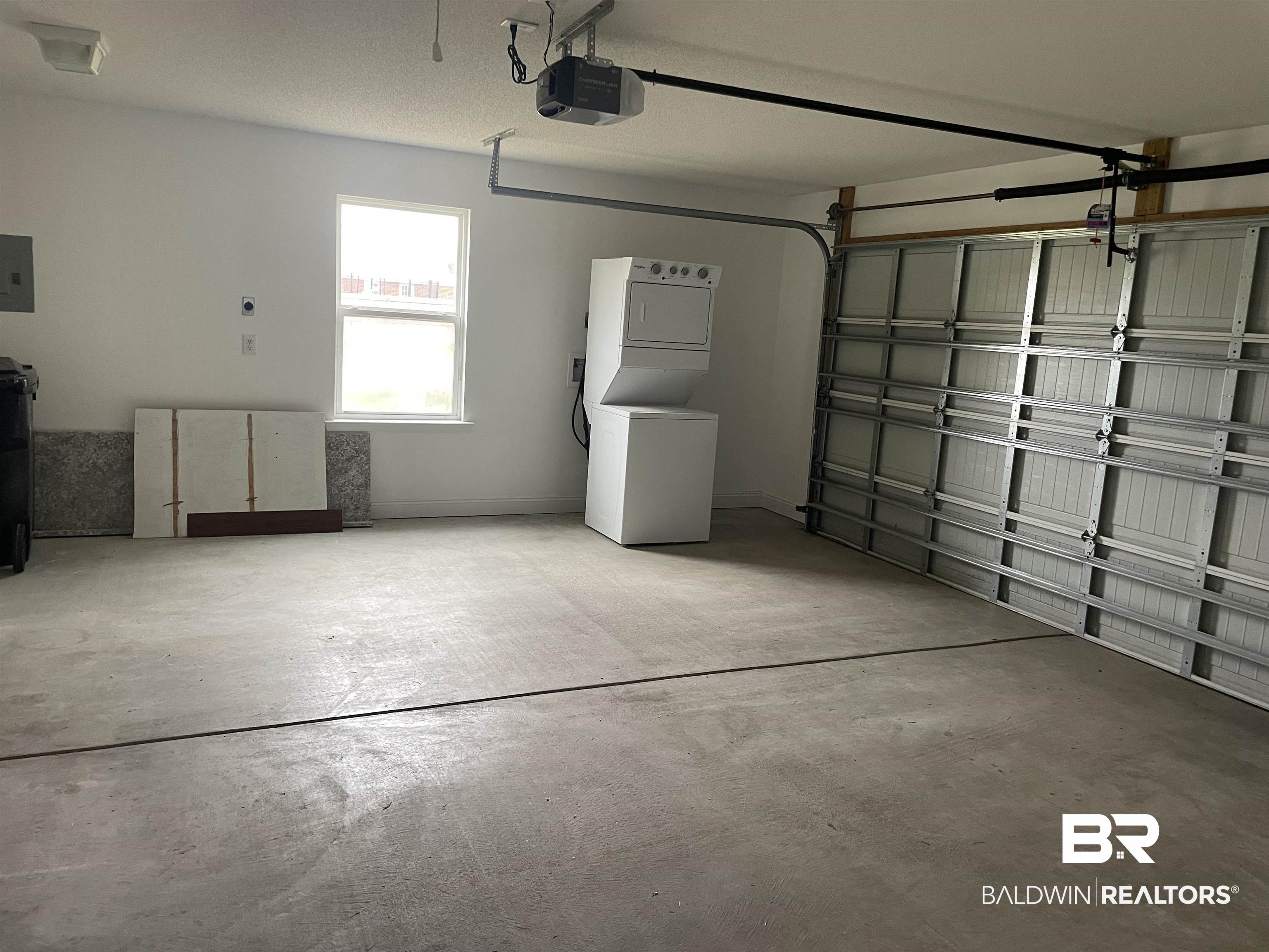 23575 Fountain Street Robertsdale, AL 36567 - Photo 8 of 19 Garage with electric panel, stacked washer and clothes dryer, and a garage door opener