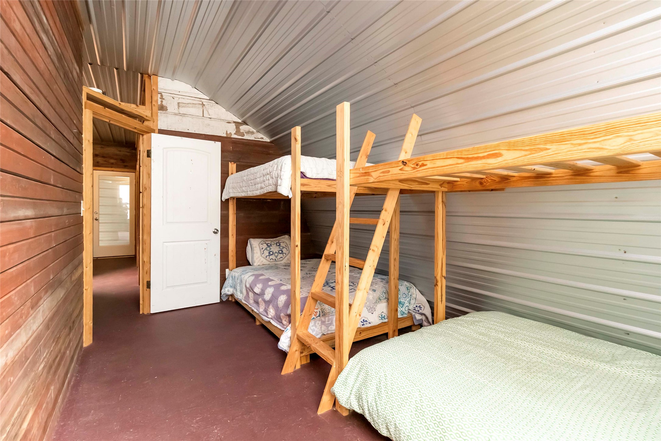 208 Old Potato Road Paige, TX 78659 - Photo 26 of 40 Bunkhouse bedroom with wooden and metal walls, finished concrete flooring, and vaulted ceiling