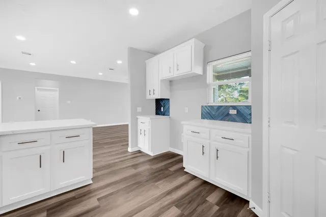 a kitchen with white cabinets and wooden floors