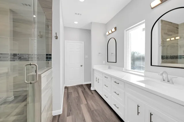 a bathroom with a double vanity sink mirror and shower