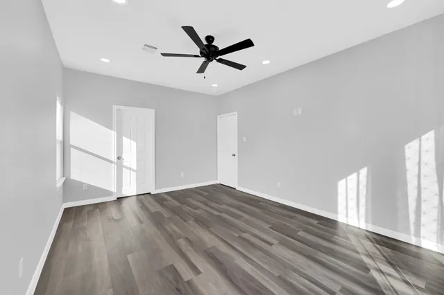 a view of empty room with wooden floor and ceiling fan