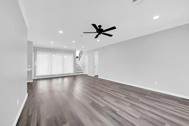 a view of empty room with wooden floor and fan