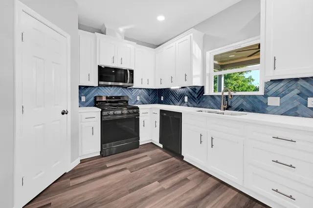 a kitchen with white cabinets appliances and a window
