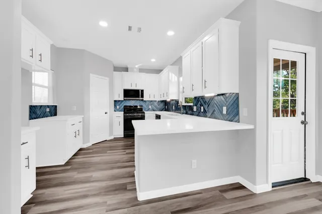 a view of kitchen with cabinets microwave and stove