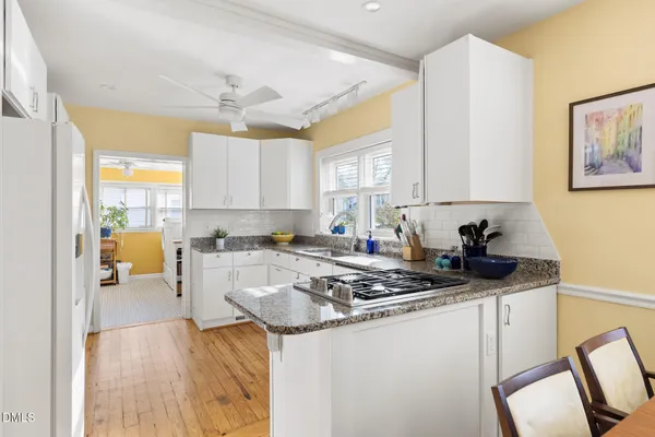 a living room with stainless steel appliances a dining table and a refrigerator