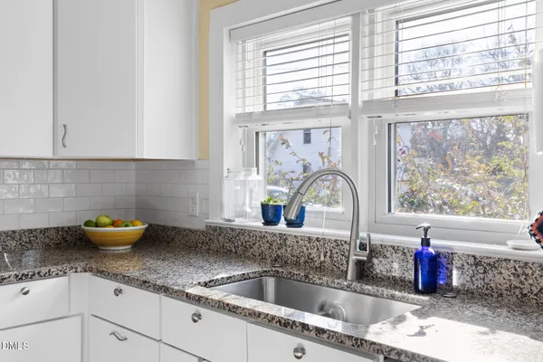 a kitchen with kitchen island granite countertop a sink cabinets and window