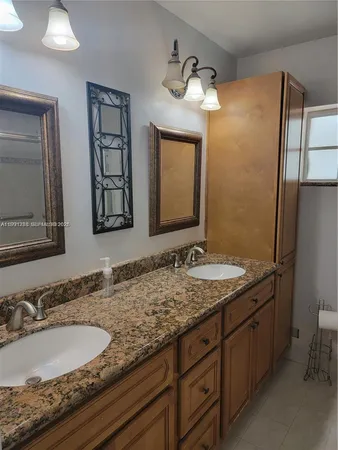 a bathroom with a granite countertop double vanity sink and a mirror