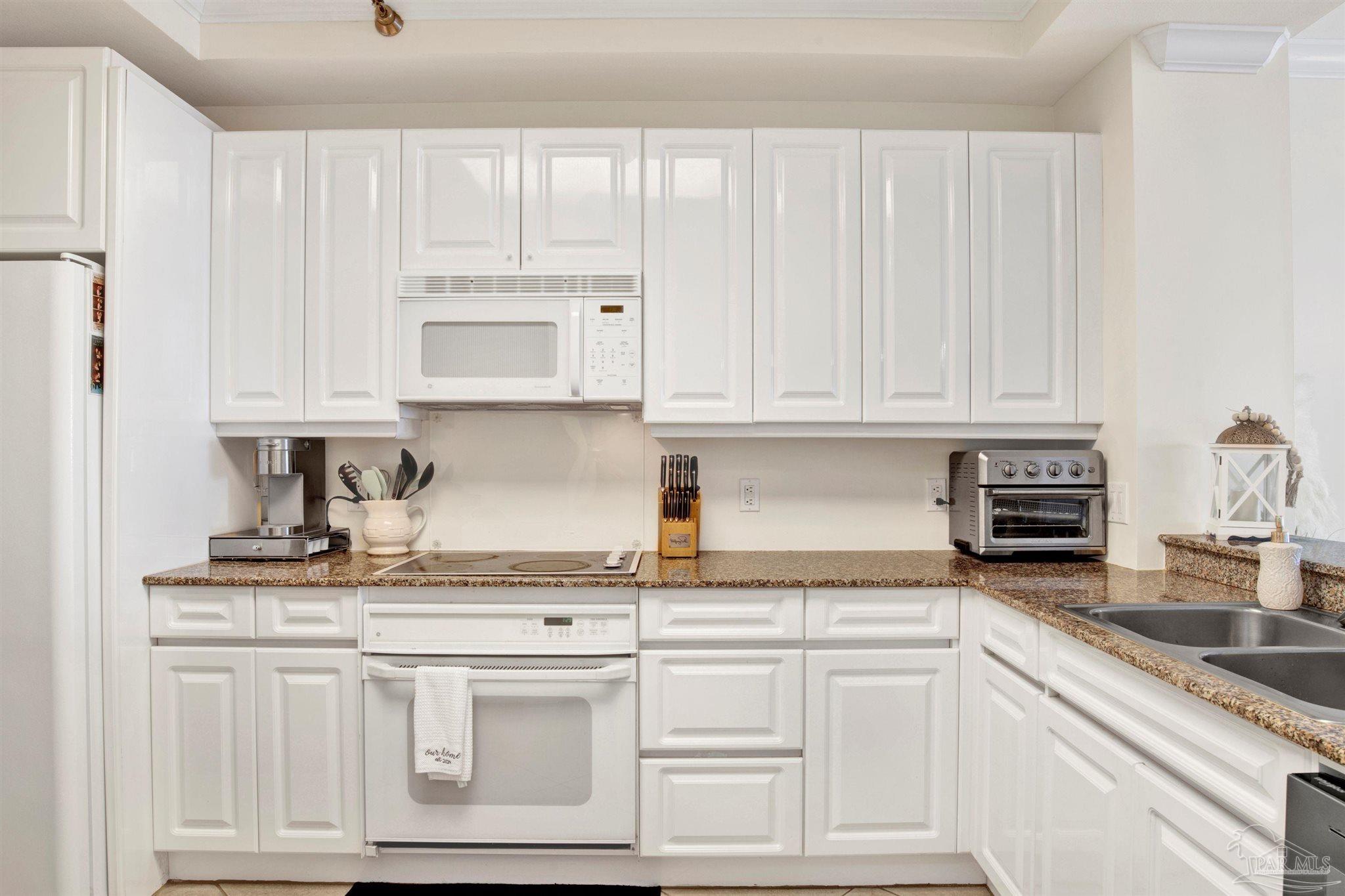 13601 Perdido Key Drive, Unit W10B Pensacola, FL 32507 - Photo 9 of 25 a kitchen with granite countertop white cabinets and white appliances