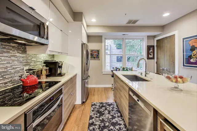 a kitchen with stainless steel appliances granite countertop a refrigerator a stove top oven a sink dishwasher and white countertops with wooden floor