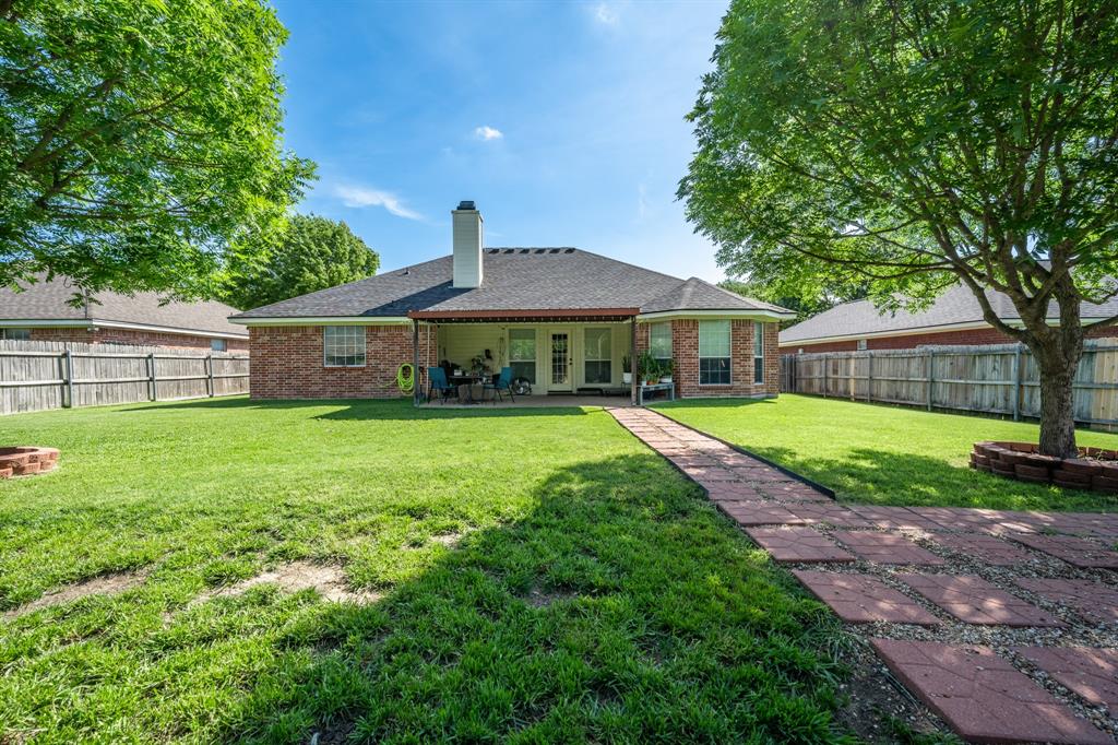 10512 Whitney Trace Drive Waco, TX 76708 - Photo 19 of 39 Expansive backyard featuring a red brick paver pathway, mature trees, an integrated brick patio, and a covered back porch