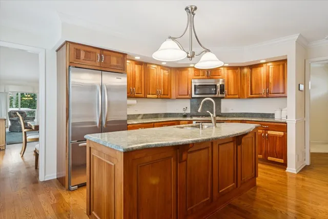 a kitchen with stainless steel appliances granite countertop a sink a refrigerator and wooden cabinets