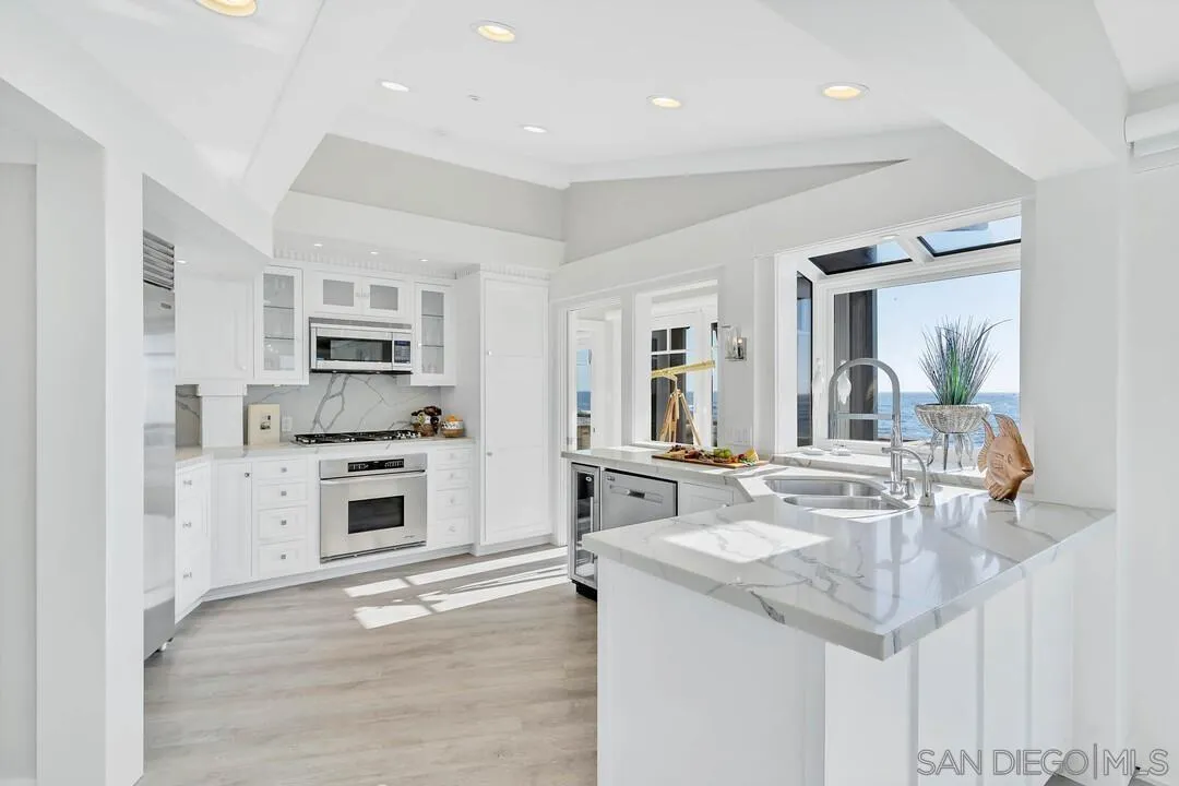 274 Coast Boulevard La Jolla, CA 92037 - Photo 17 of 64 a kitchen with stainless steel appliances granite countertop a stove oven and a refrigerator with white cabinets