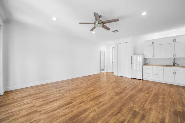 an empty room with wooden floor fan and windows