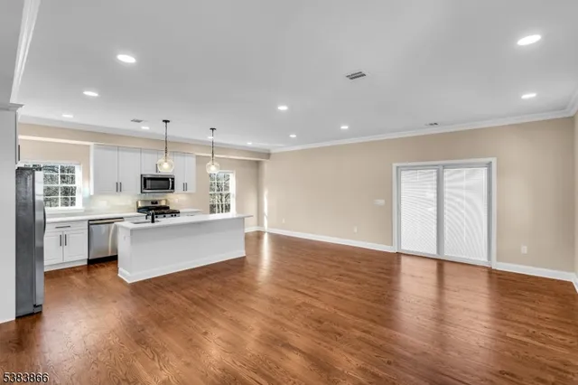 a large kitchen with stainless steel appliances granite countertop a large center island a sink a stove and a refrigerator