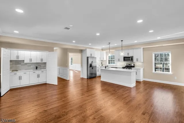 a large kitchen with white cabinets stainless steel appliances and wooden floor