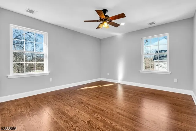 a view of an empty room with window and wooden floor