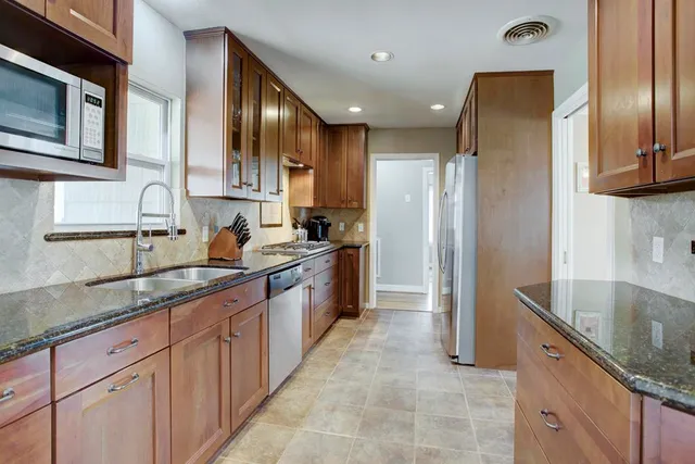 a large kitchen with stainless steel appliances granite countertop a sink and a refrigerator