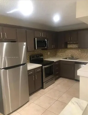 a kitchen with stainless steel appliances granite countertop a refrigerator and a stove top oven
