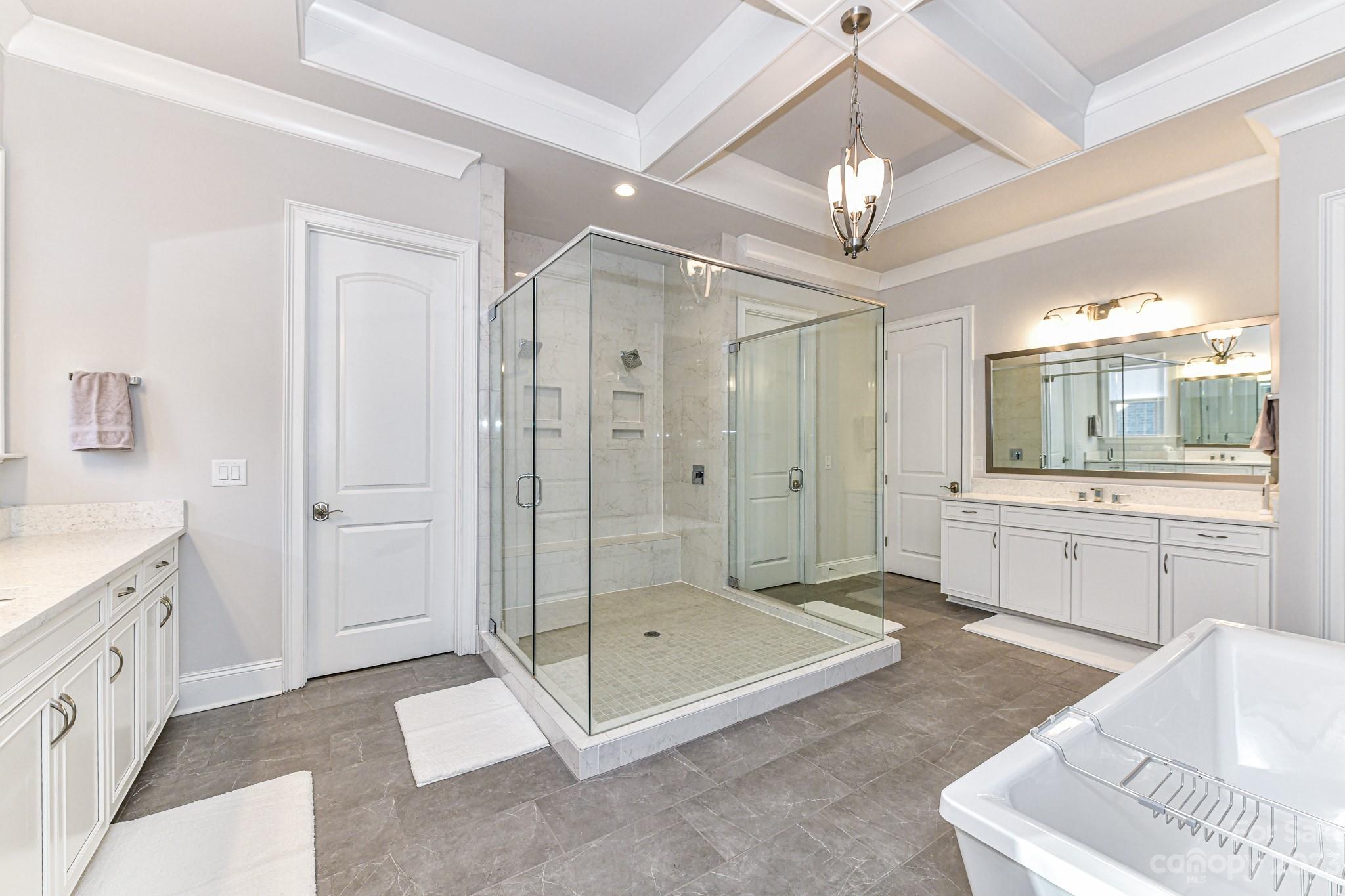 125 Turtleback Ridge, Unit 122 Matthews, NC 28104 - Photo 20 of 40 a spacious bathroom with a granite countertop sink a mirror a shower and a bathtub