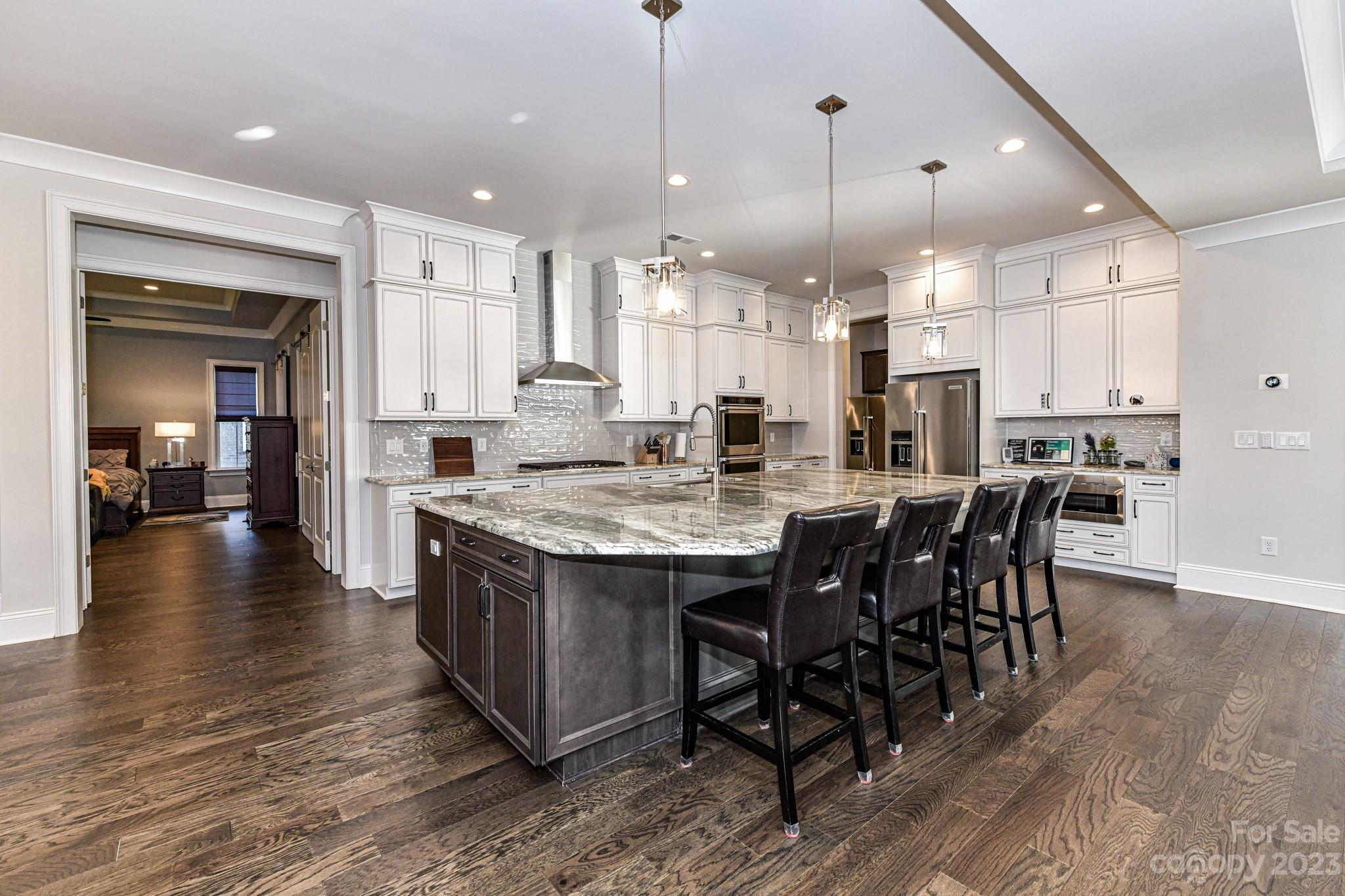125 Turtleback Ridge, Unit 122 Matthews, NC 28104 - Photo 9 of 40 a large kitchen with kitchen island a dining table chairs and a wooden floor