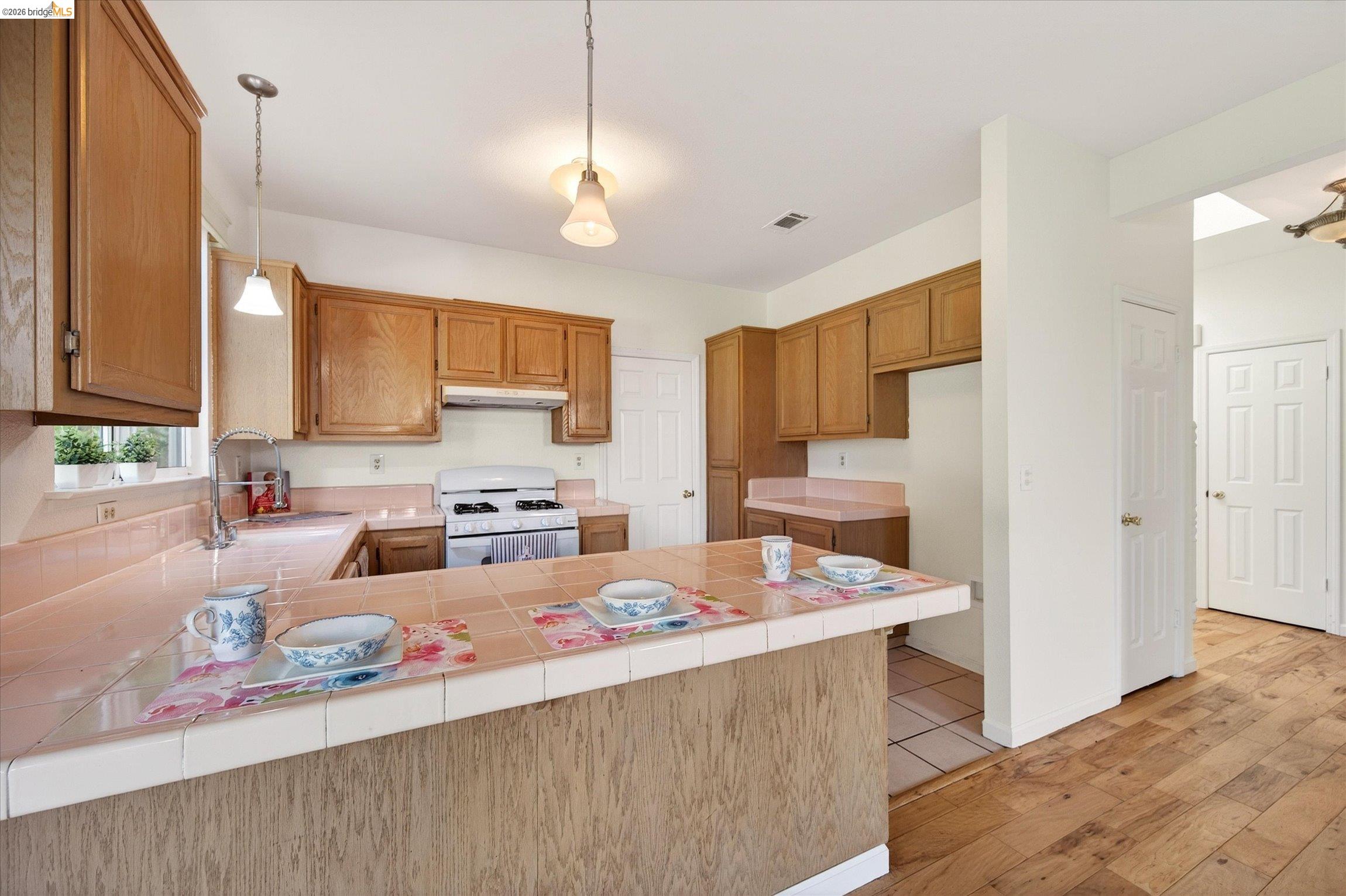 1120 Deerpark Road Oakley, CA 94561 - Photo 13 of 30 Kitchen featuring wood cabinetry, tiled countertops, a white gas range, and a breakfast bar