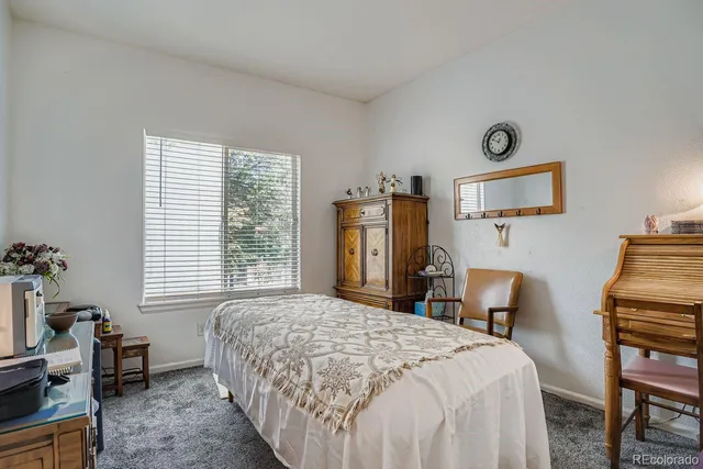 a bedroom with a bed table chair and a window
