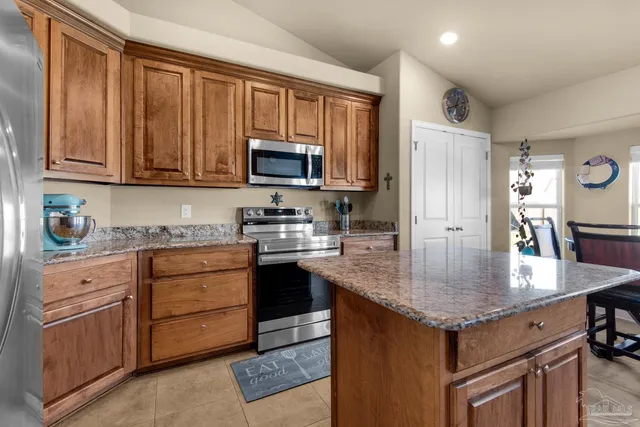 a kitchen with kitchen island granite countertop a stove top oven microwave and refrigerator