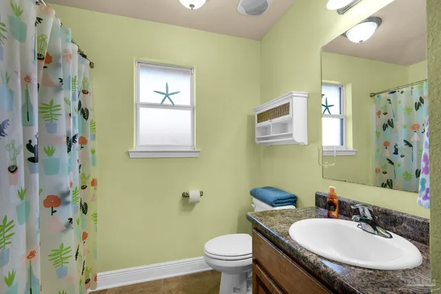 a bathroom with a granite countertop toilet a sink and a mirror